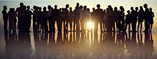 a gathering of people in silhouette with a bright setting sun